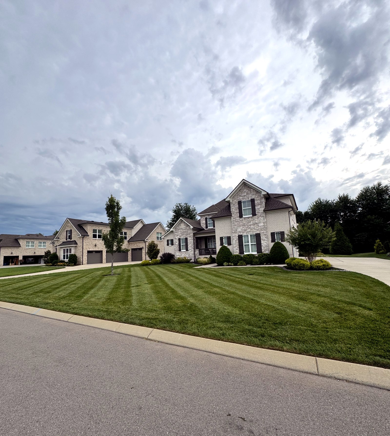 A large home with a crisply striped front lawn and dramatic sky